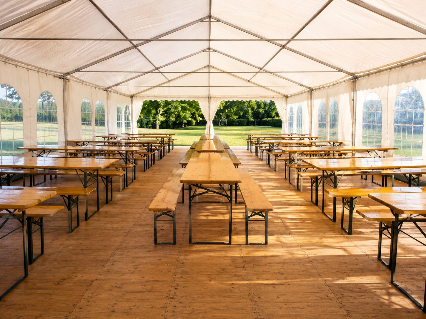 Blick in ein helles Festzelt mit langen Reihen aus Biertischgarnituren